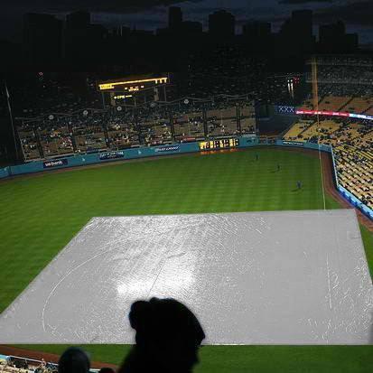 170' x 170' baseball tarp protecting the playing field beneath stadium lights at night