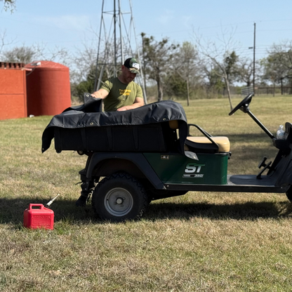 Black waterproof canvas tarp to cover utility cart bed outdoors; ideal for equipment protection in farm or yard settings.