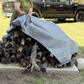 Gray waterproof canvas tarp with brass grommets used to cover stacked firewood outdoors; ideal for moisture protection and long-term storage.