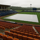 Empty stadium with a white tarp over the field on a cloudy day