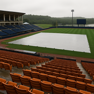Empty stadium with a white tarp over the field on a cloudy day