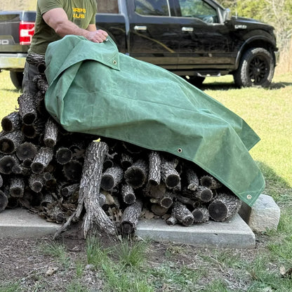 Green 5' x 7' canvas tarp protecting stacked firewood from outdoor weather exposure