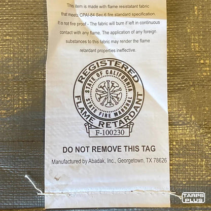 Silver 12' x 20' tarp cover displaying manufacturing approval tag information