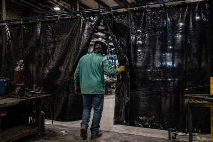 Worker entering black tarp containment area through zipper door used for welding curtain and industrial partition